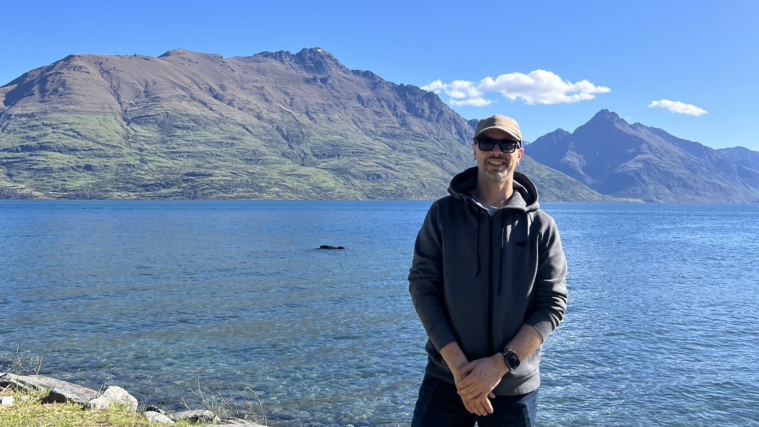 Robert Lech standing by a lake with mountains in the background